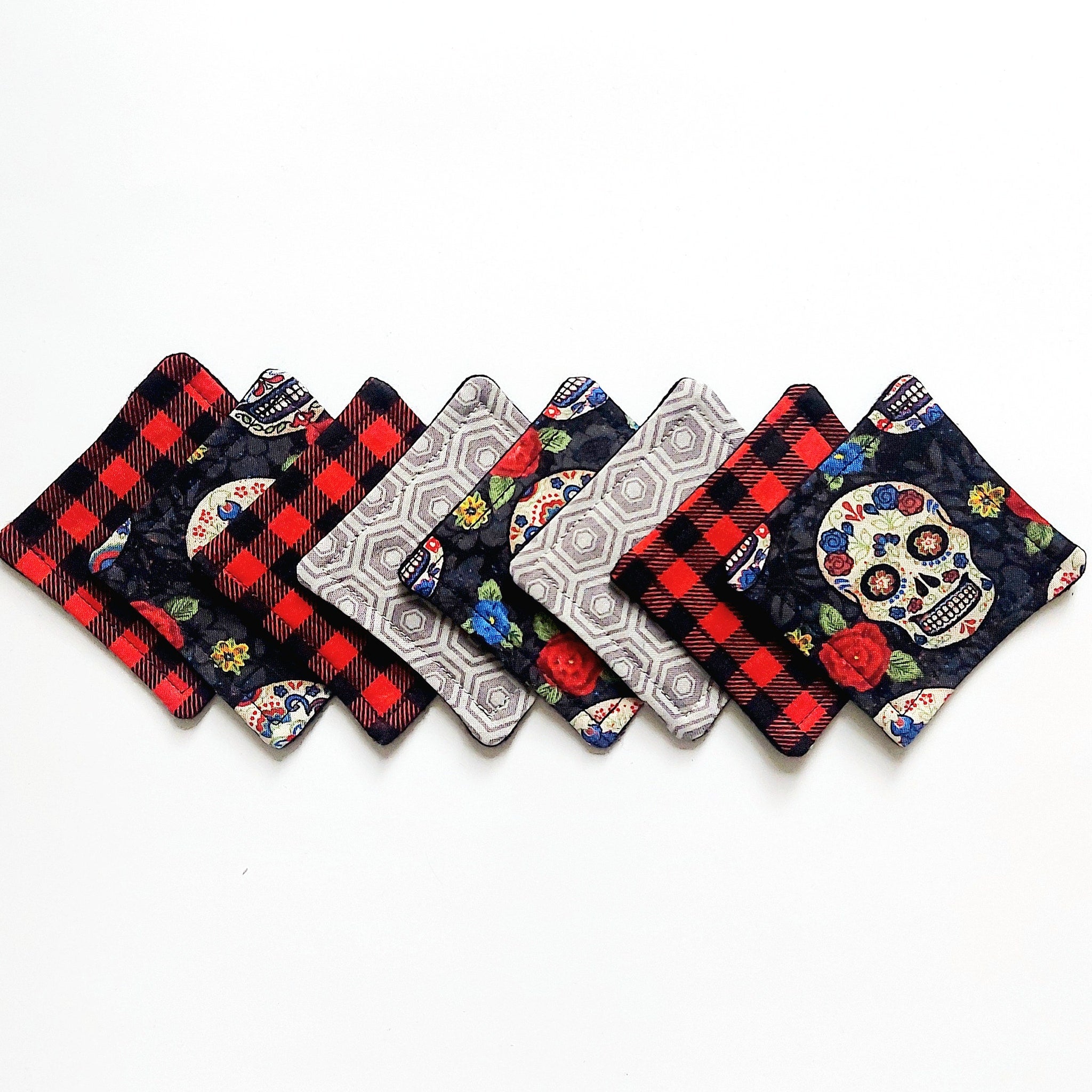 Coasters with red plaid, skull, and geometric patterns in various colors, fabric material