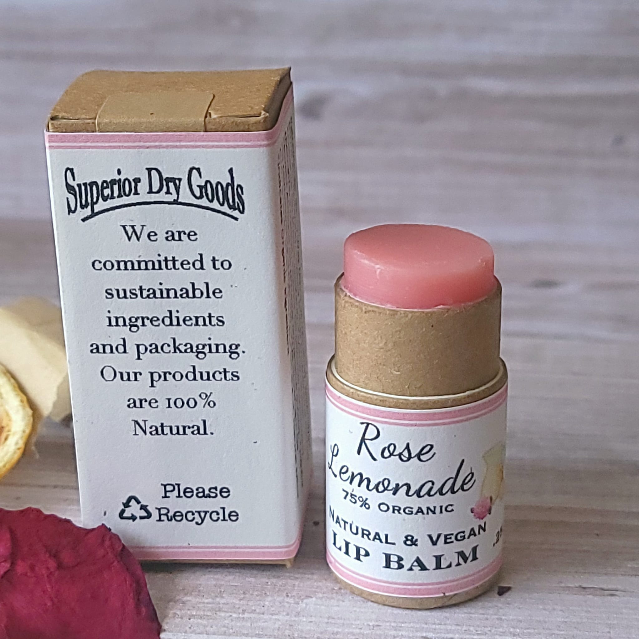 Lip balm with pink color, cardboard tube, and Rose Lemonade label next to a box