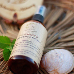 Sunscreen bottle with brown glass, cream label, and Artemisia Alchemy text on a natural background