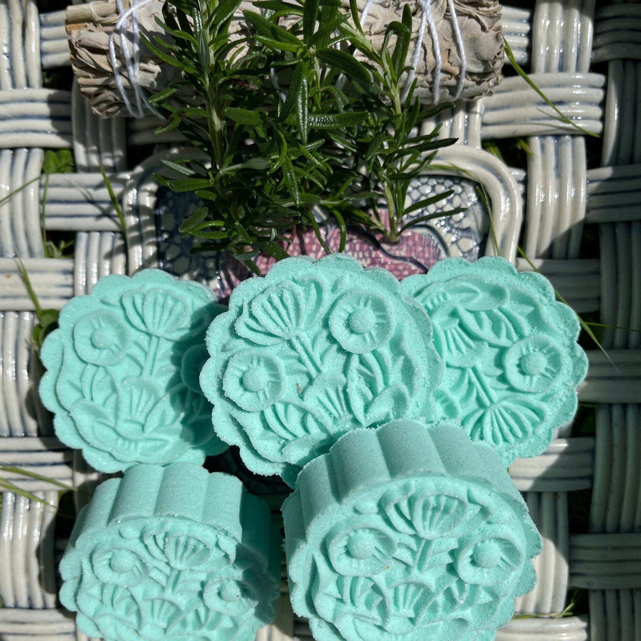 Bath bombs, turquoise floral pattern, round shape, on woven surface with herbs