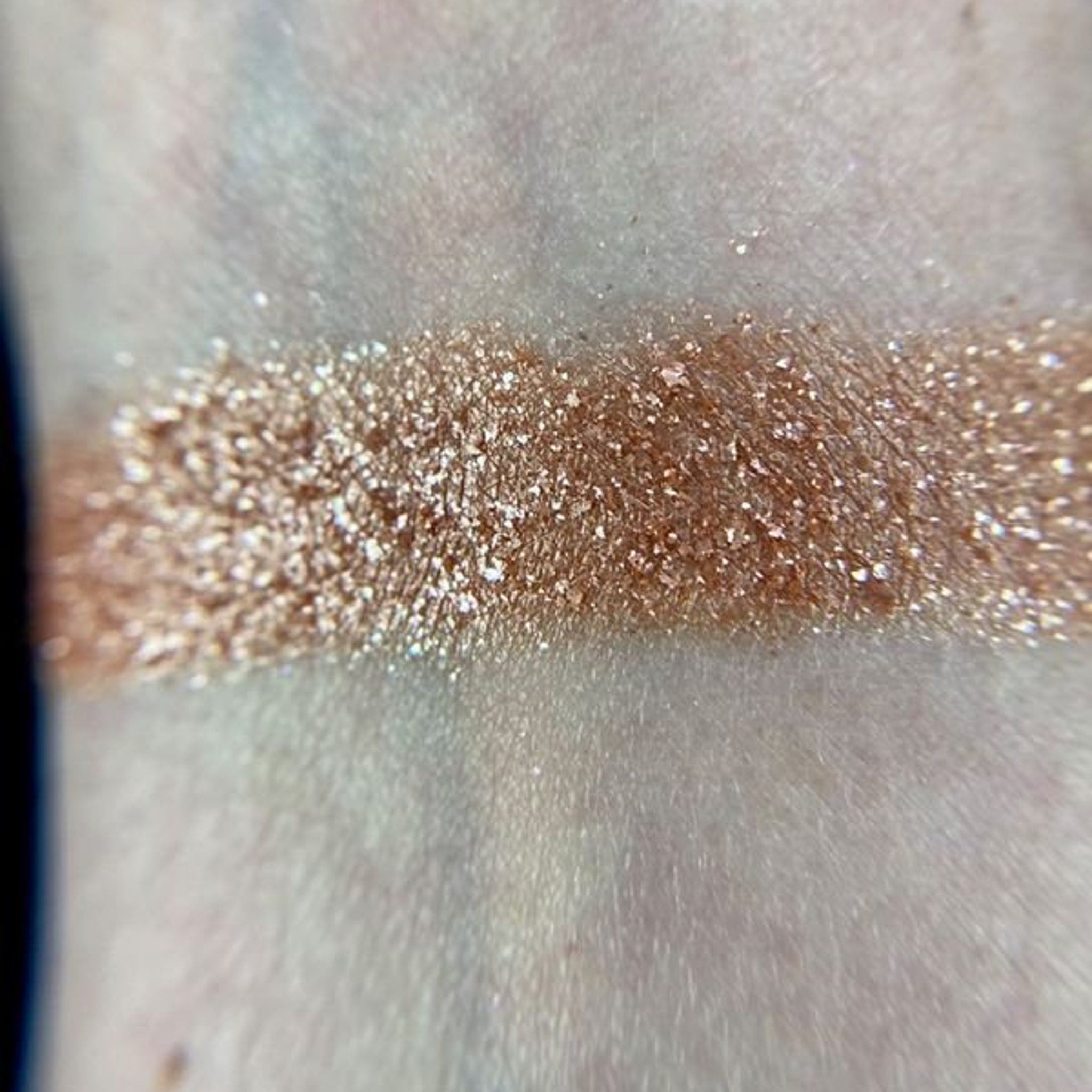 Close-up of Io Eye Shadow Palette showing shimmering bronze and plum shades with smooth, blendable texture