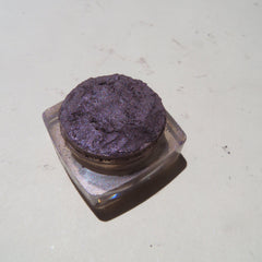 Hand applying dark black purple shimmer loose mineral eyeshadow with a brush for a smoky eye look
