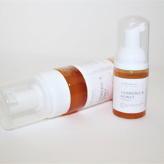 Face wash bottles with white plastic, clear pump tops, and amber liquid, Ahima Beauty brand visible