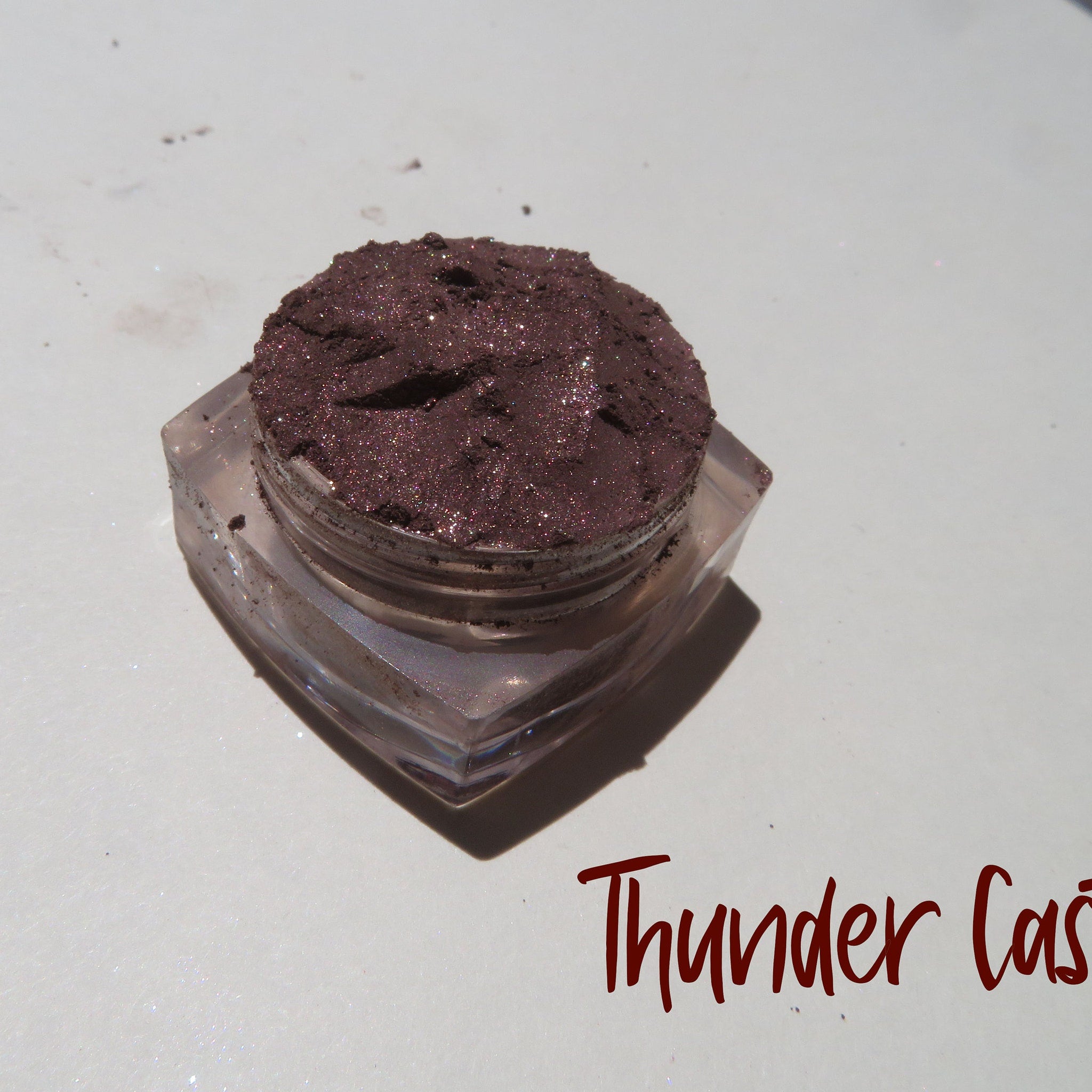 Side view of dark brown shimmer mineral loose eye shadow in eco-friendly packaging with metallic finish