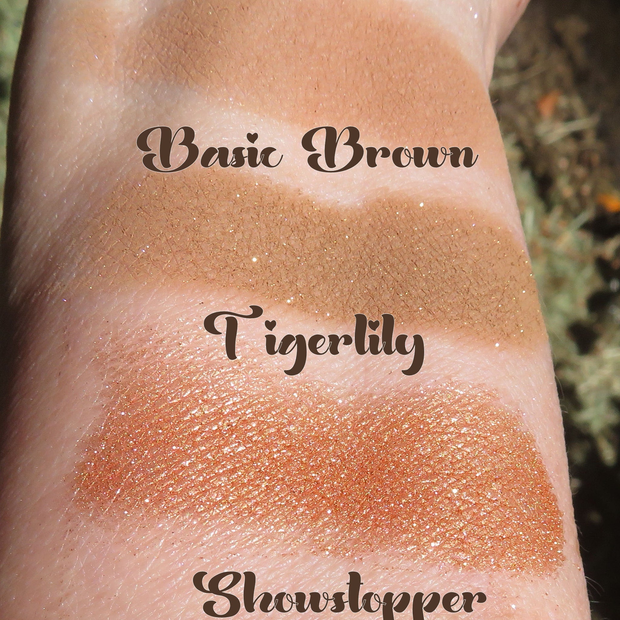 Three autumn-inspired mineral eyeshadows in brown shimmer shades displayed on a rustic wooden tray