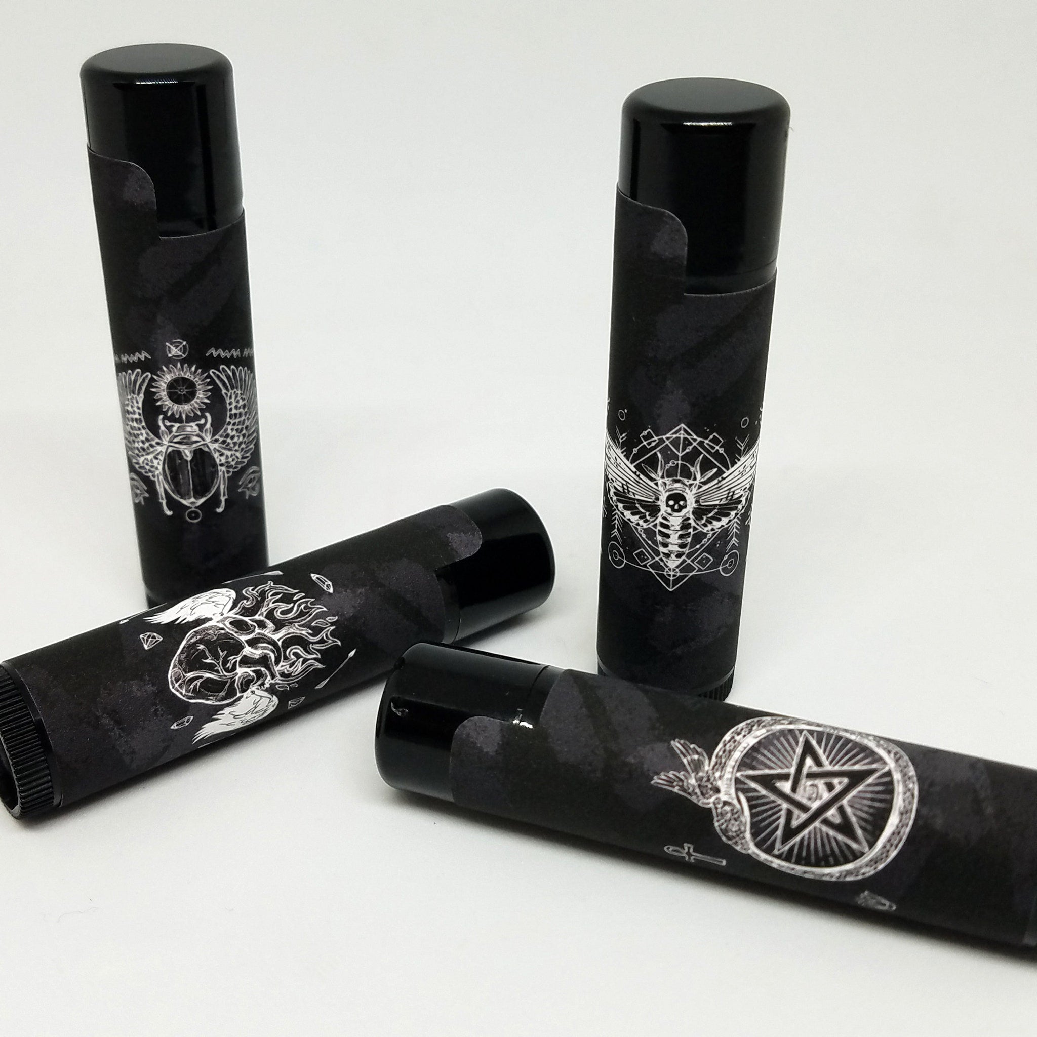 Black lip balm tubes with white graphic designs and black caps, various patterns