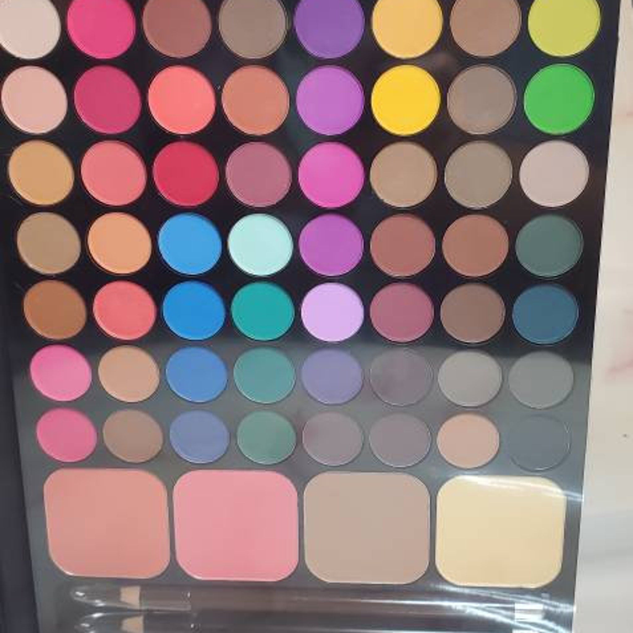 Eyeshadow palette with multiple round and square pans in various colors for makeup application