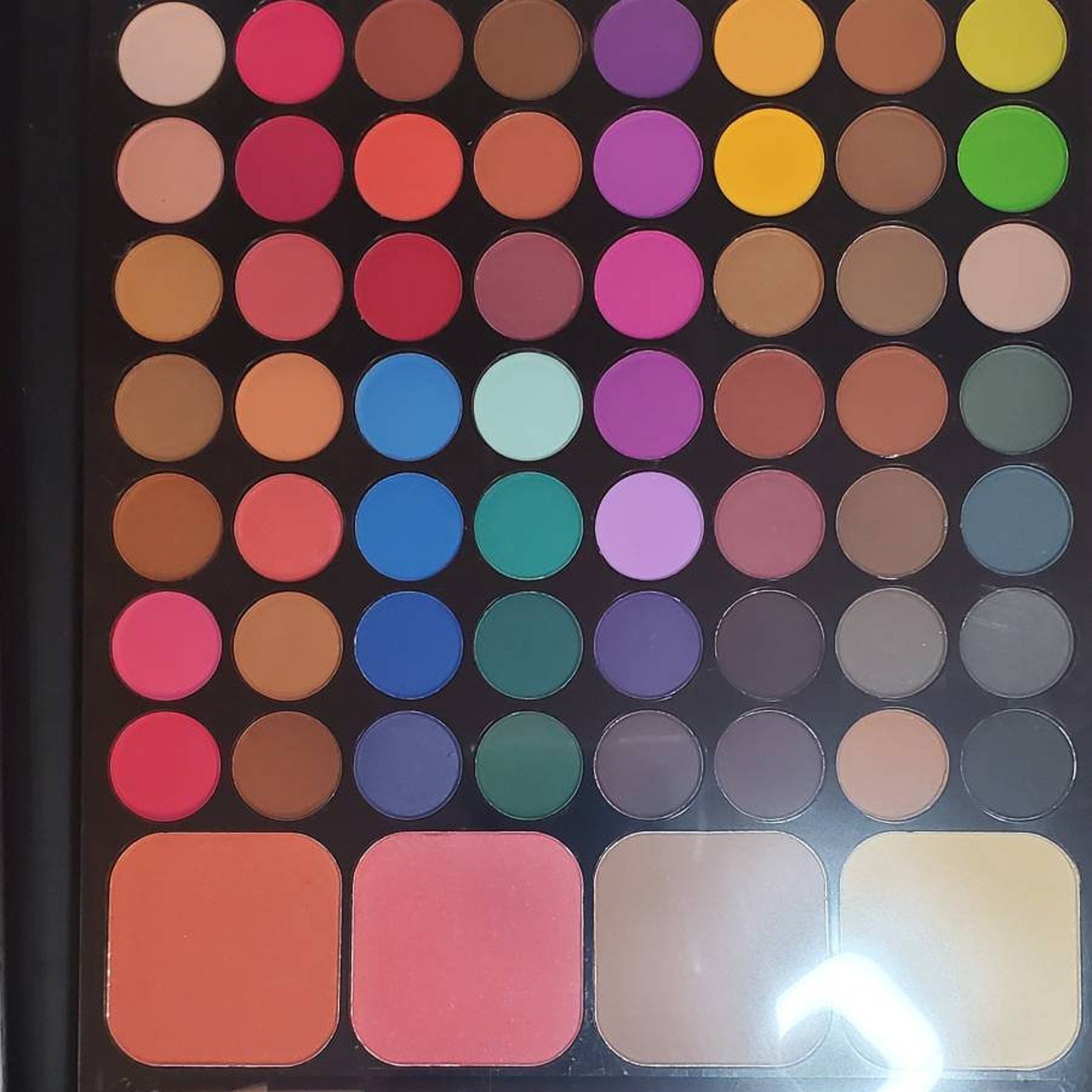 Eyeshadow palette with multiple colorful round eyeshadows and blush, black case
