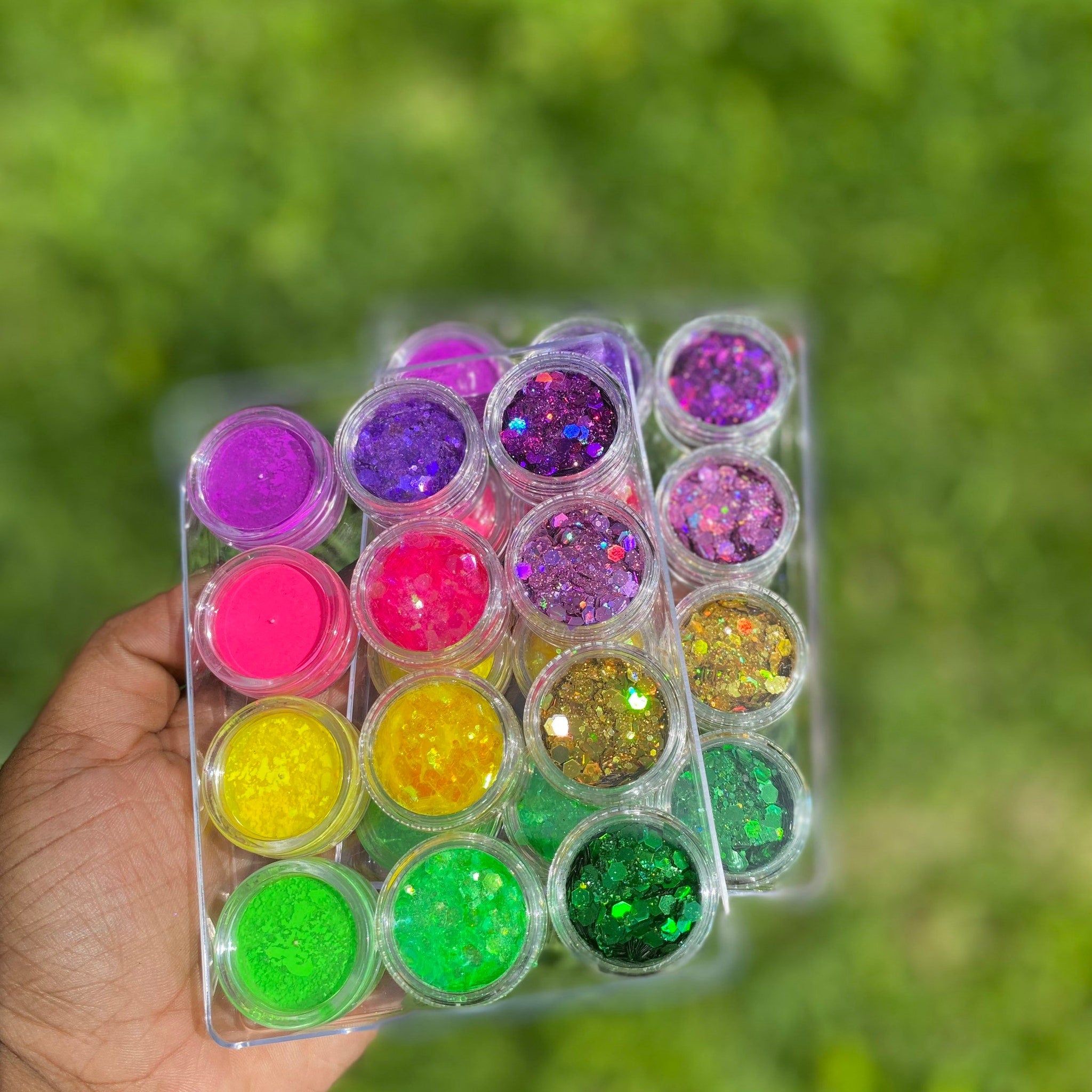 Side view of glitter makeup palette showing stacked pans with rainbow hues and mirrored compact design