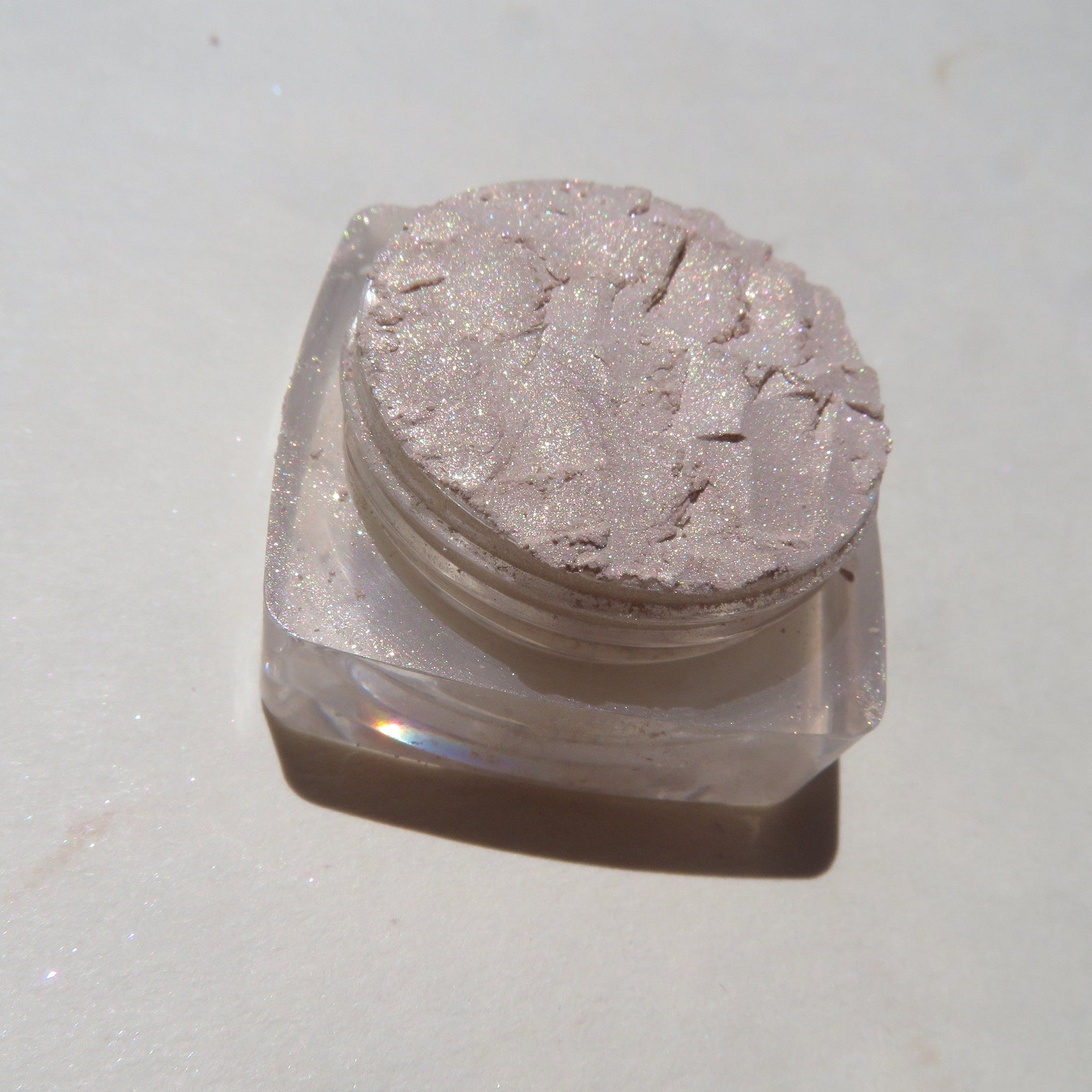 Close-up of loose mineral eyeshadow in pale yellow shimmer with golden flecks, vegan and cruelty-free