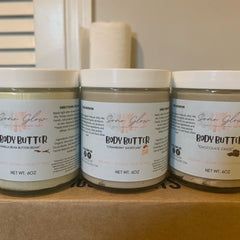 Close-up of creamy vanilla bean body butter being smoothed onto dry skin with fingertips, showcasing rich texture