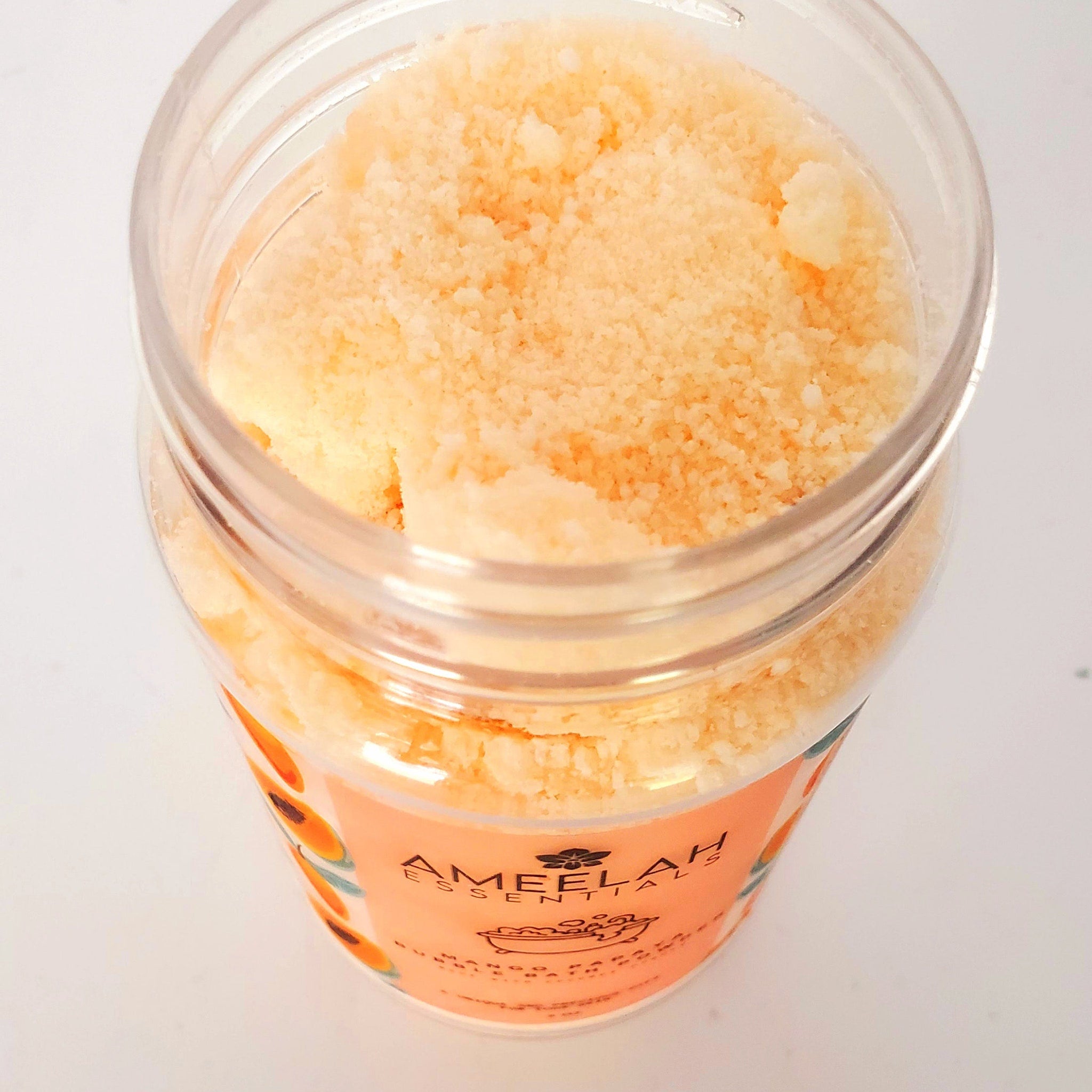 Bath powder in clear jar with orange powder, Ameelah Essentials branding visible on label, white background
