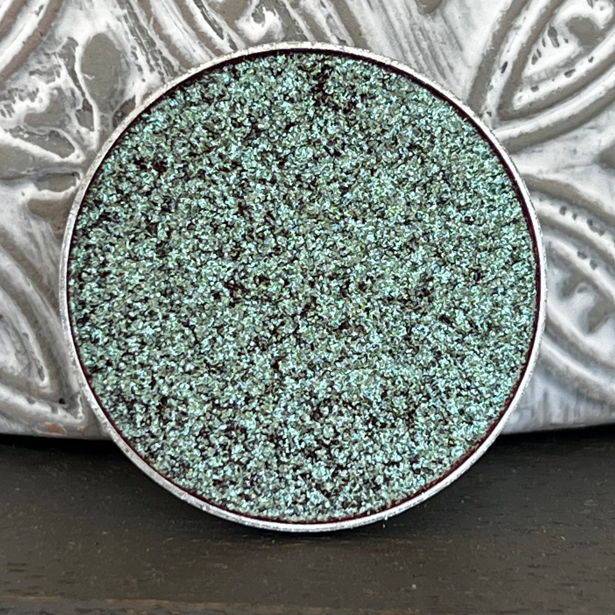 Close-up of holographic tea green eyeshadow with multi-chrome color shift in pressed pan
