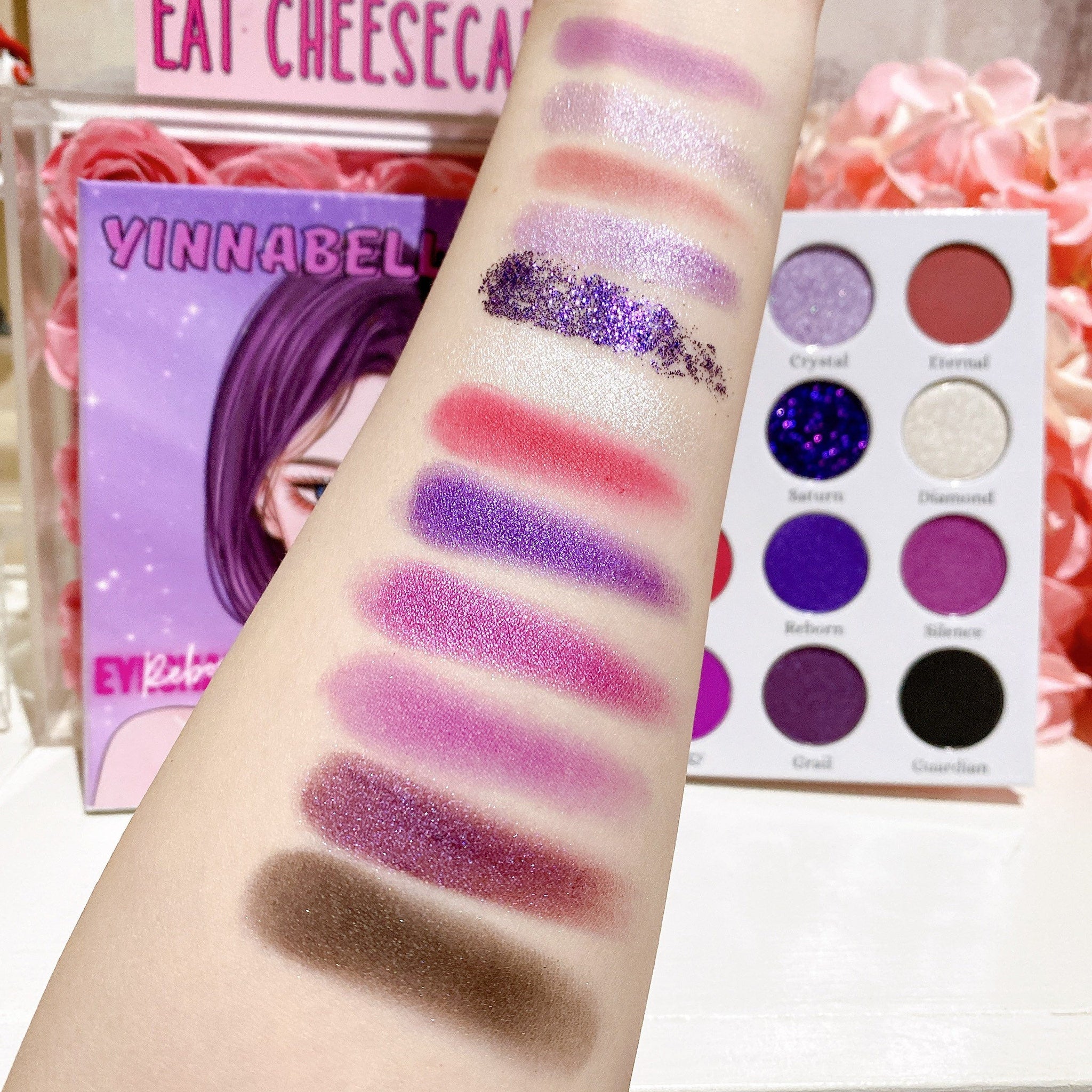 Close-up of fingers applying shimmery purple eyeshadow with a blending brush, showcasing smooth pigment payoff
