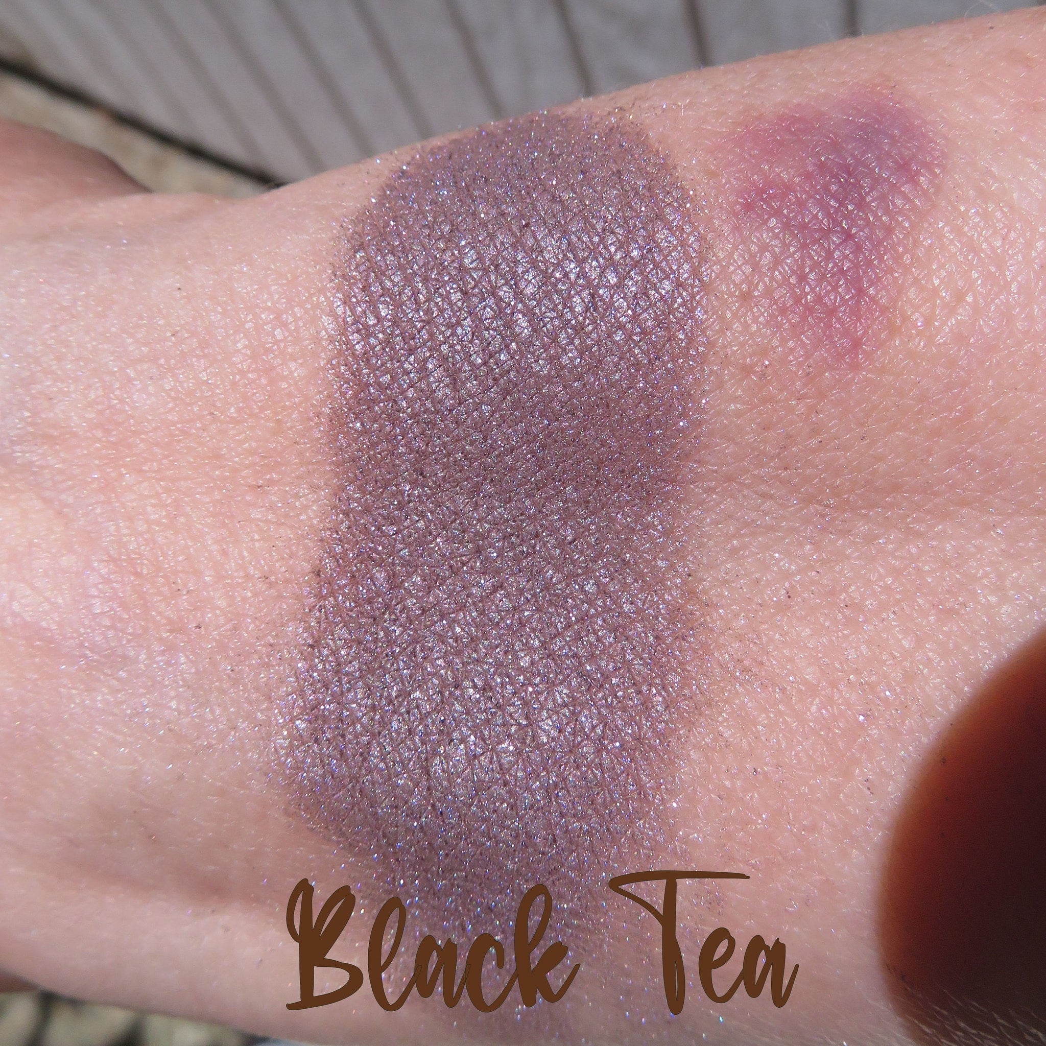 Side view of dark black purple shimmer loose mineral eyeshadow in eco-friendly packaging with metallic sheen
