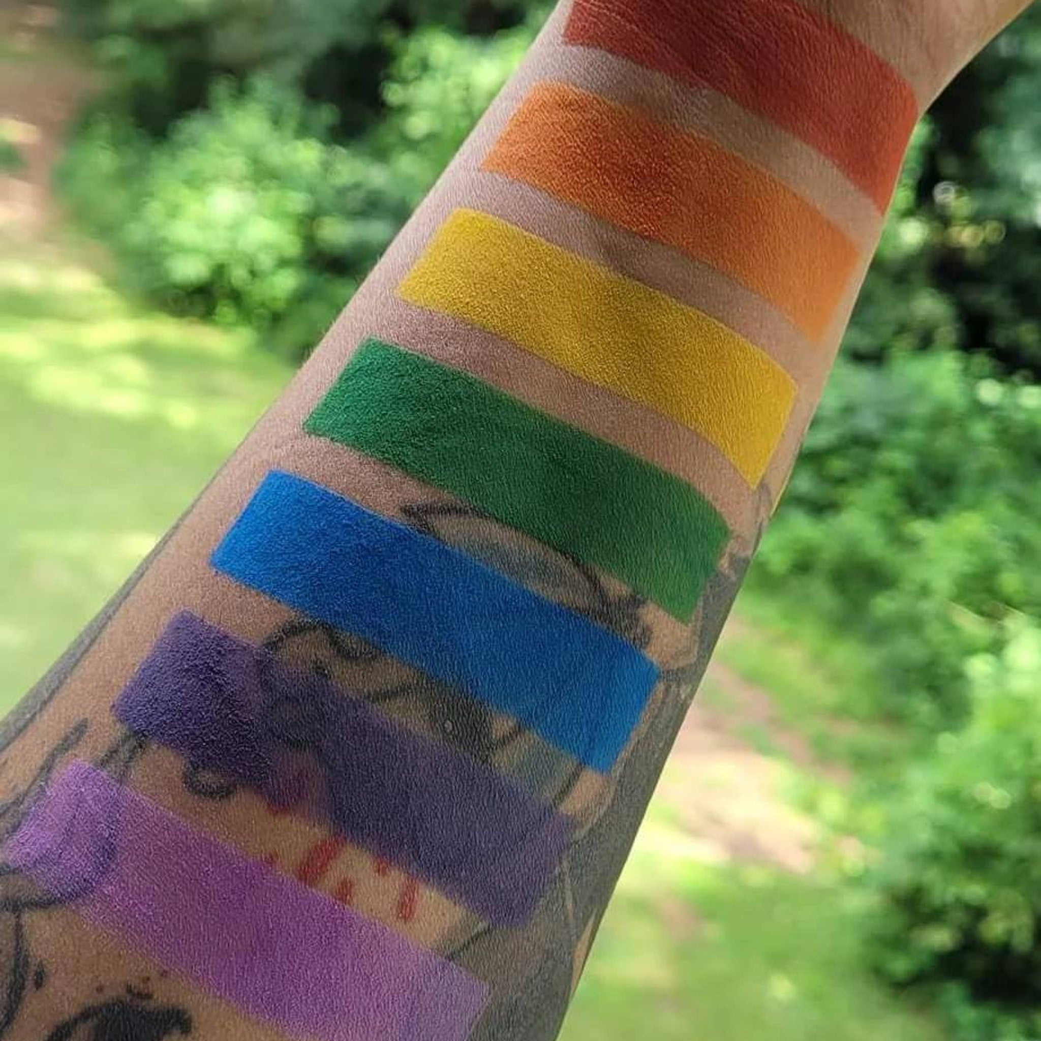 Side view of rainbow pride eyeshadow palette showing seven matte shades in angled display