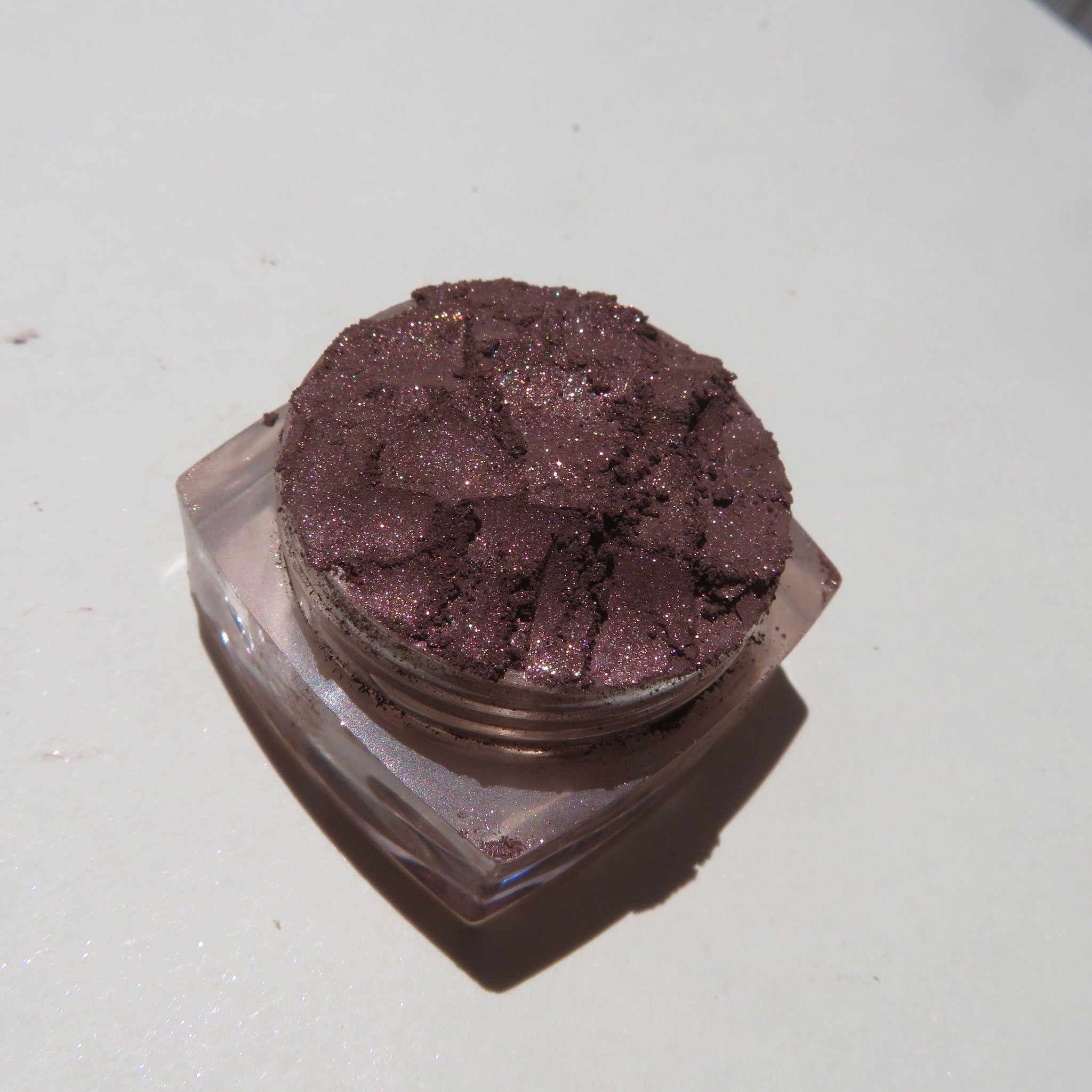 Side view of dark brown shimmer mineral loose eye shadow in eco-friendly packaging with metallic accents