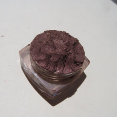 Side view of dark brown shimmer mineral loose eye shadow in eco-friendly packaging with metallic accents