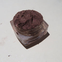 Hand applying dark brown shimmer mineral loose eye shadow with a fluffy brush for a smoky eye look
