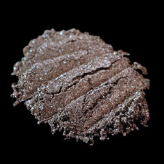 Side view of loose pigment eyeshadow in cool bronze with metallic brown base and silver glitter flecks