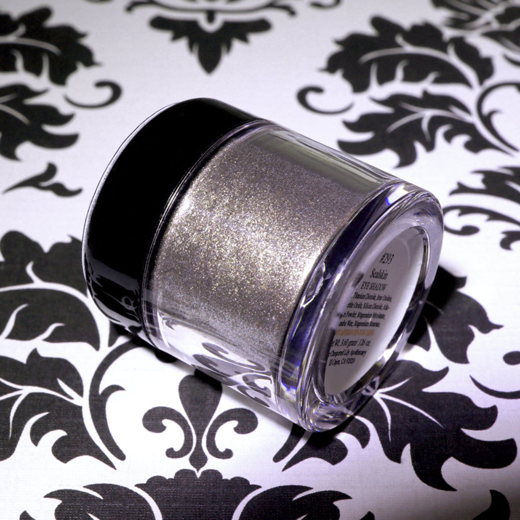 Close-up of loose pigment eyeshadow in cool bronze with silver and blackened gold glitter particles shimmering