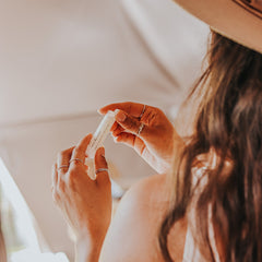 Lip balm tube, white with black text, held in hands with rings