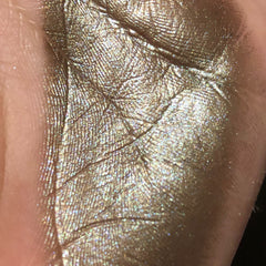 Side view of Celebration Eyeshadow single in sleek black compact with shimmering champagne powder visible