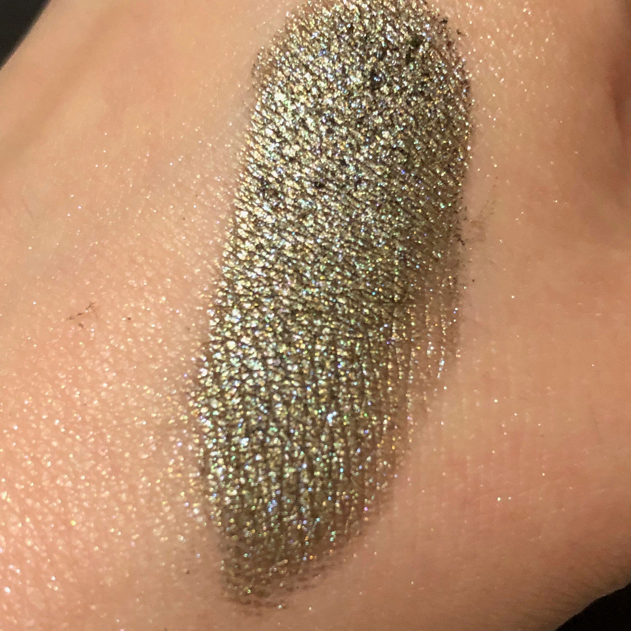 Woman applying shimmering champagne eyeshadow to eyelid with fingertip for a soft, blended look