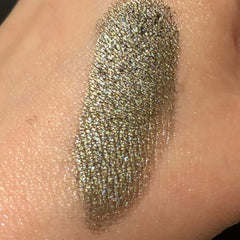 Woman applying shimmering champagne eyeshadow to eyelid with fingertip for a soft, blended look