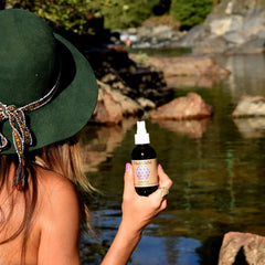 Spray bottle held by hand with "PAAVANI" label, dark bottle, white spray top, outdoors