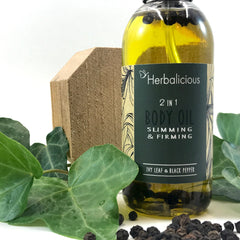 Body oil bottle with yellow liquid, dark label, and wooden block, Herbalicious brand