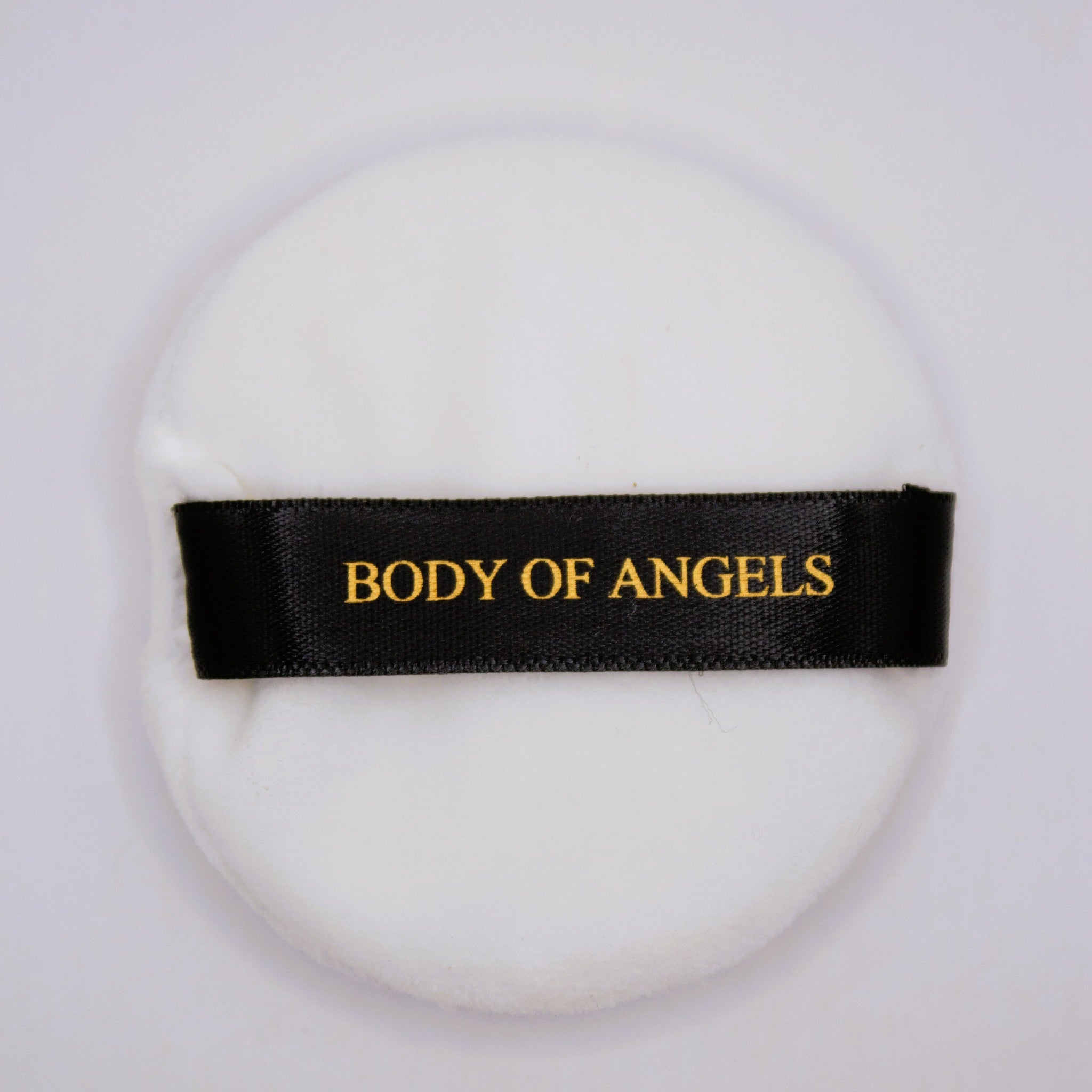 Powder puff, white round with black band, "BODY OF ANGELS" text in gold lettering