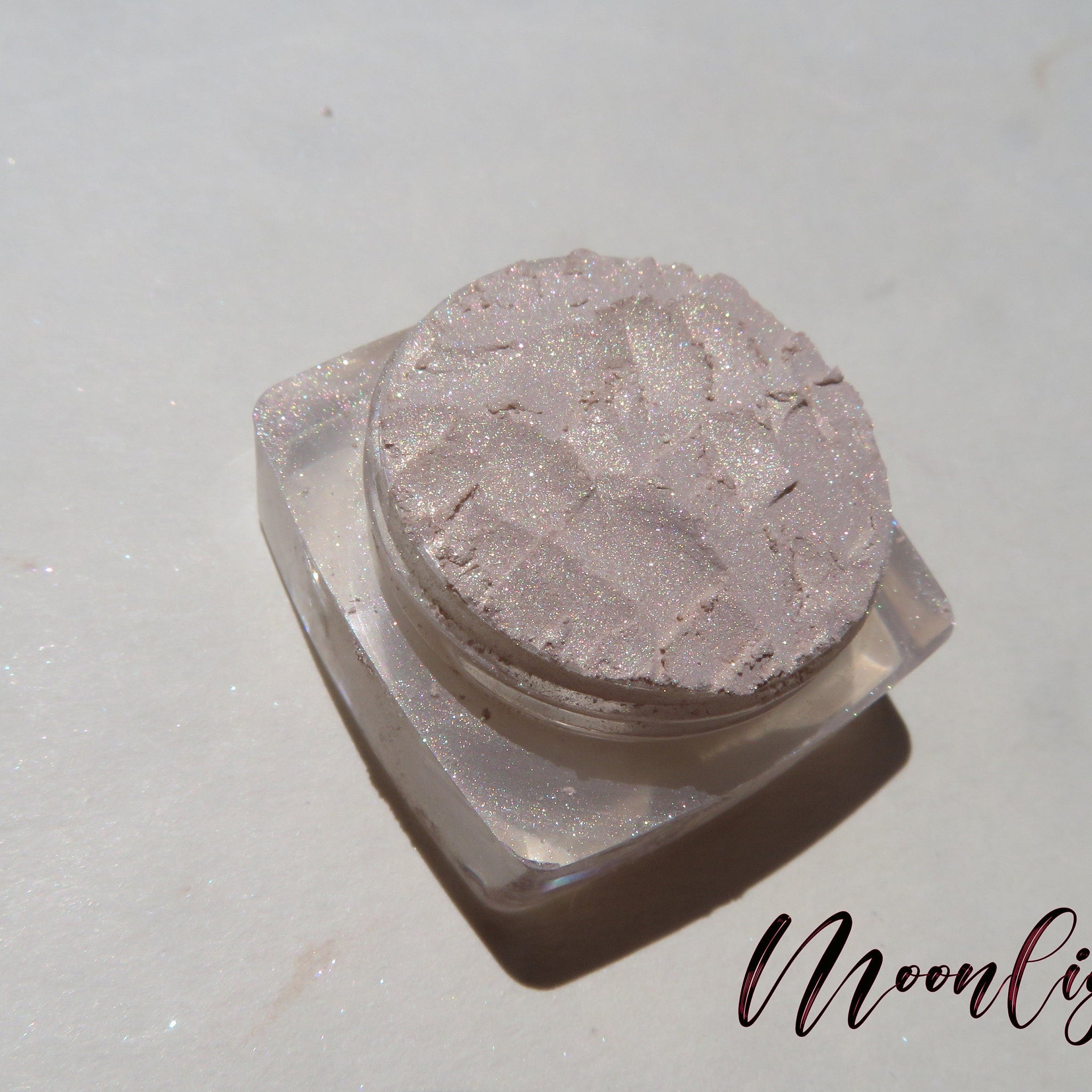 Side view of loose mineral eyeshadow in shimmering pale yellow with golden flecks, showcasing fine powder texture