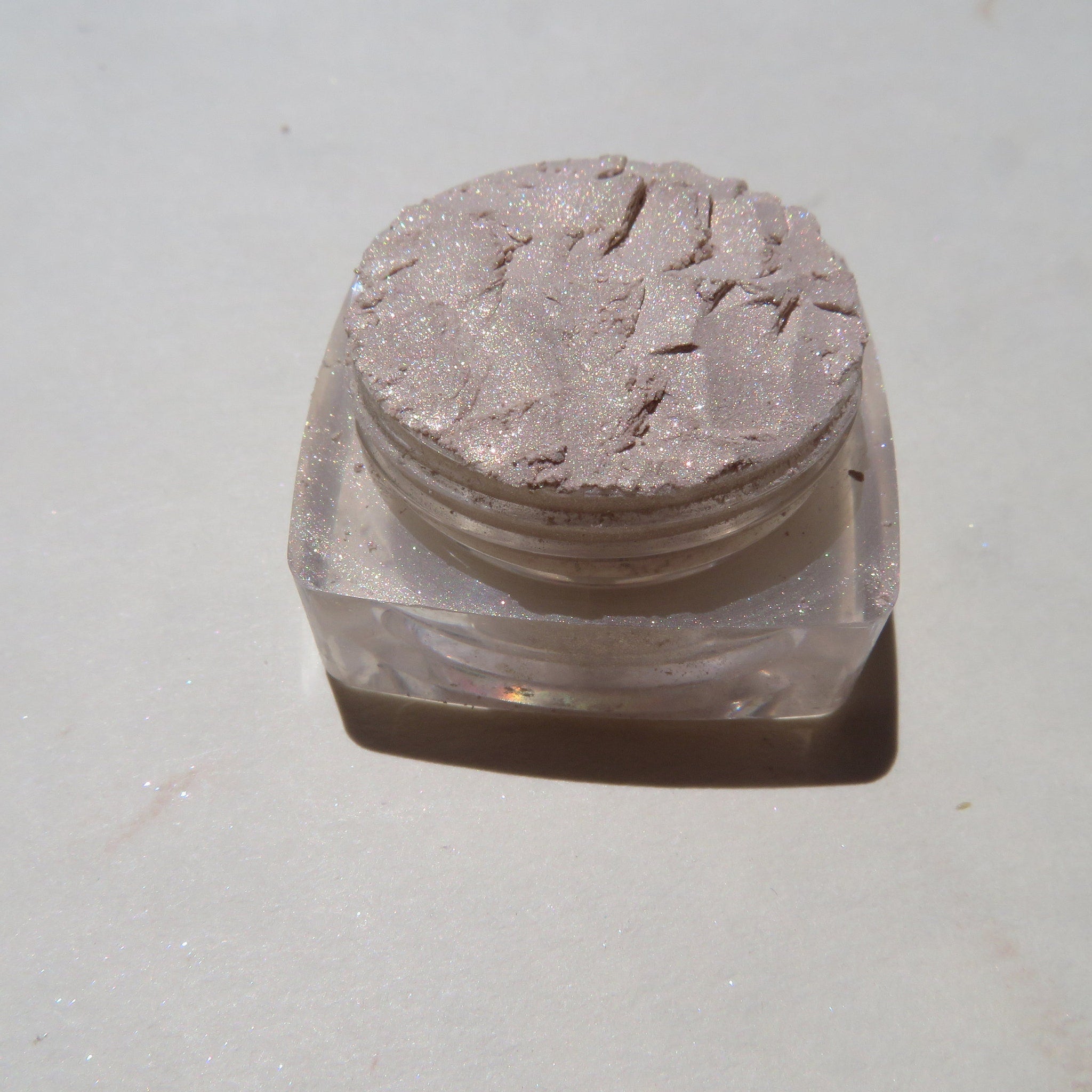 Hand applying pale yellow shimmer loose powder eyeshadow with a brush for a golden glow
