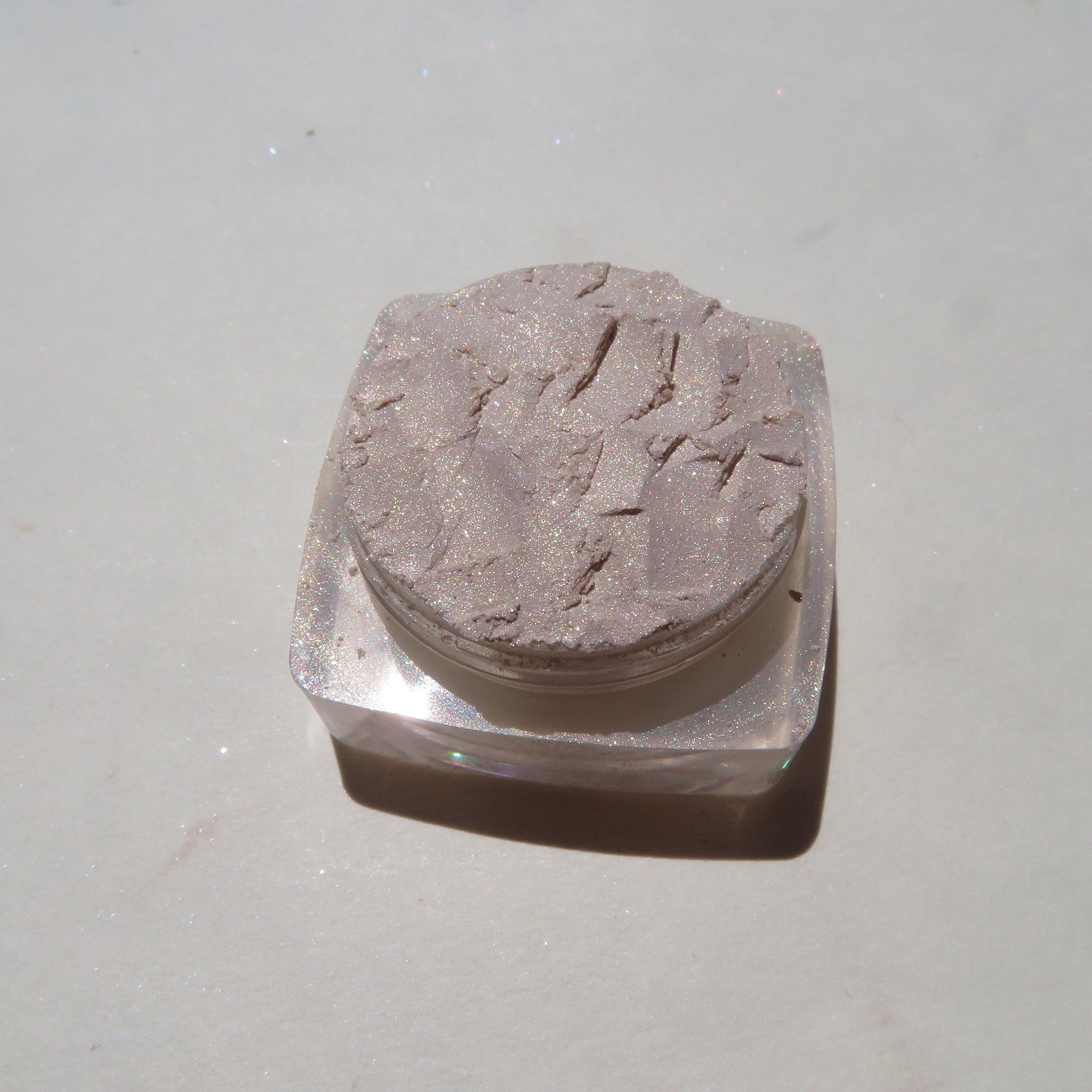 Close-up of loose pale yellow shimmer eyeshadow with golden flecks, showcasing fine mineral powder texture