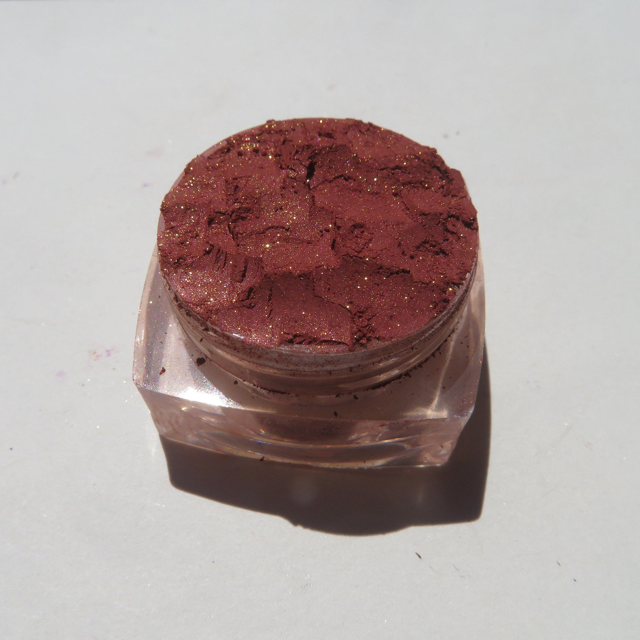 Close-up of brick red orange shimmer loose mineral eyeshadow with sparkling flecks in eco-friendly packaging