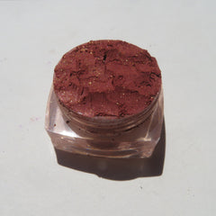 Close-up of brick red orange shimmer loose mineral eyeshadow with sparkling flecks in eco-friendly packaging