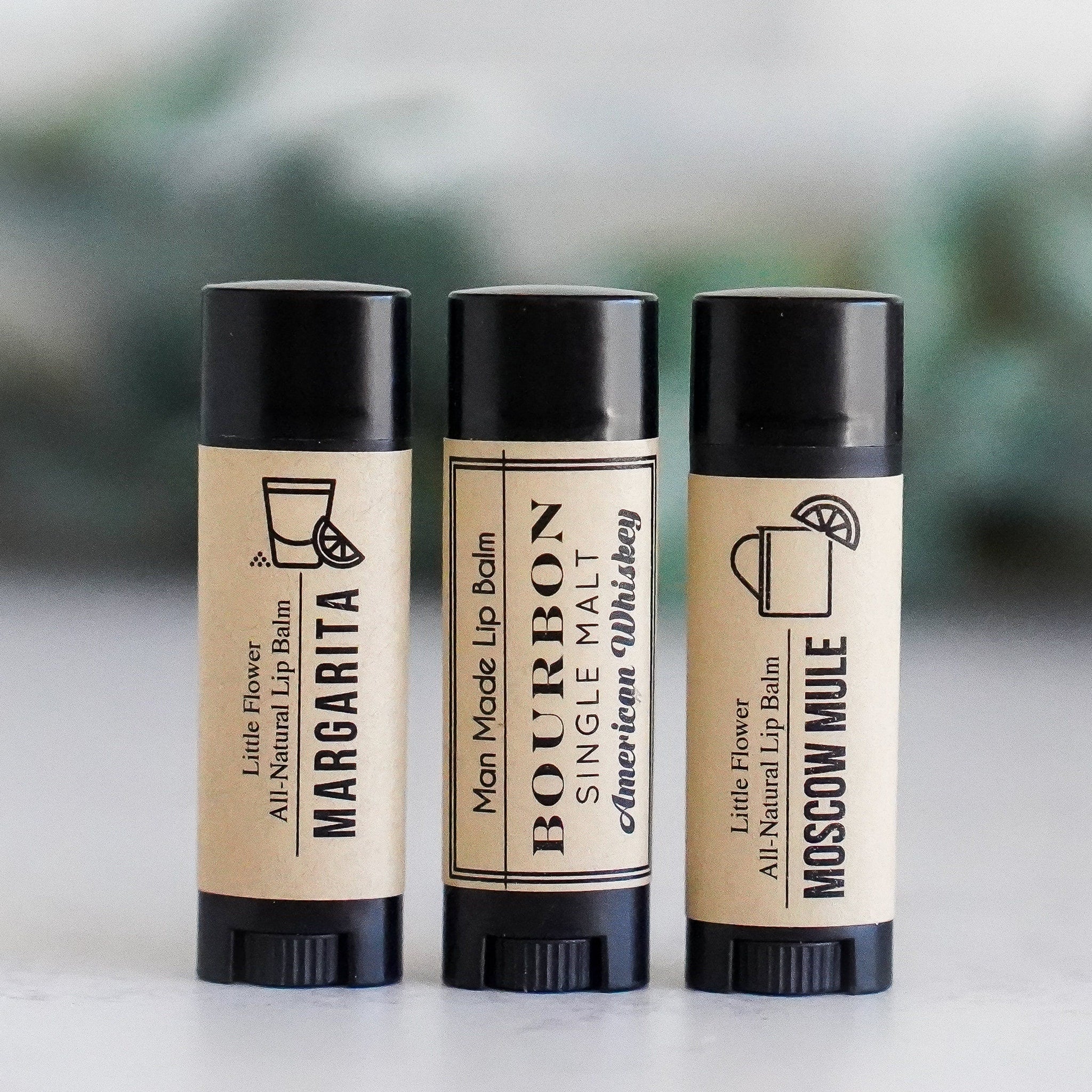 Lip balms with black tubes and tan labels, Little Flower Soap Co brand, Margarita, Bourbon, and Moscow Mule flavors