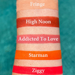 Lipstick swatches in orange, red, and pink shades on skin, with text labels "Starman" and "Ziggy" visible
