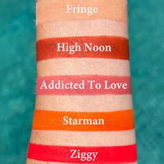 Lipstick swatches, orange, red, and pink colors on skin, with names visible: Fringe, High Noon, Addicted To Love, Starman, Ziggy