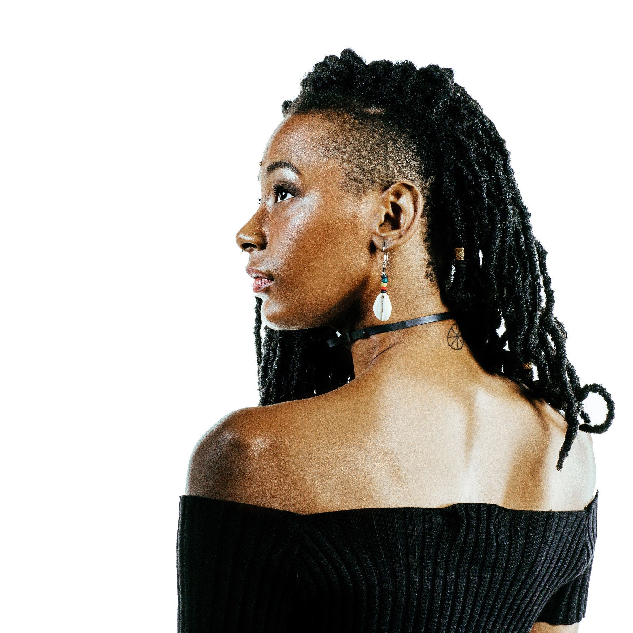 Woman with black dreadlocks, black off-shoulder top, and black choker necklace in profile view