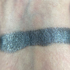 Hand applying shimmery bronze eye shadow from palette to eyelid with blending brush