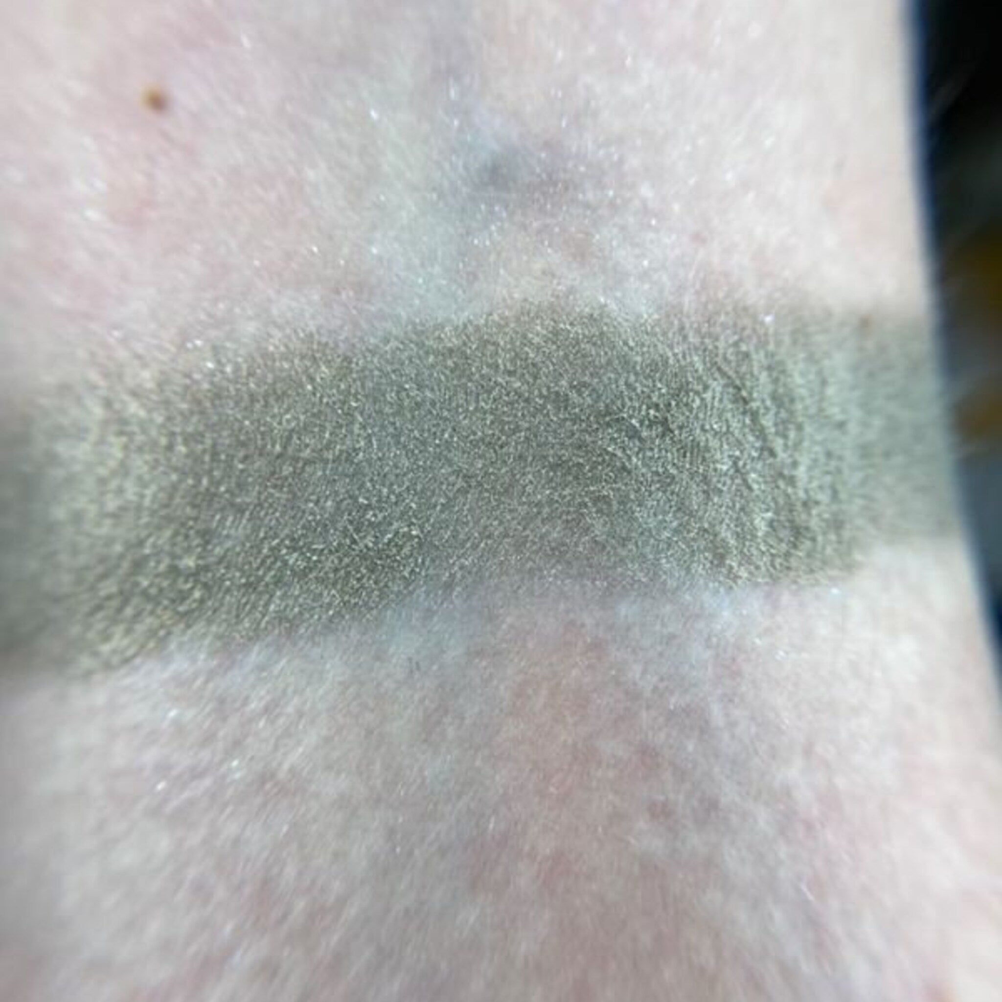 Close-up of fingertips applying vibrant orange Betelgeuse eye shadow to eyelid with smooth blending motion