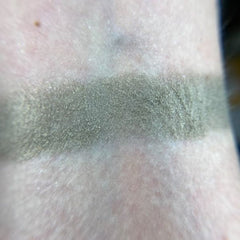 Close-up of fingertips applying vibrant orange Betelgeuse eye shadow to eyelid with smooth blending motion