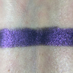 Close-up of makeup brush applying shimmery bronze eye shadow from palette to eyelid