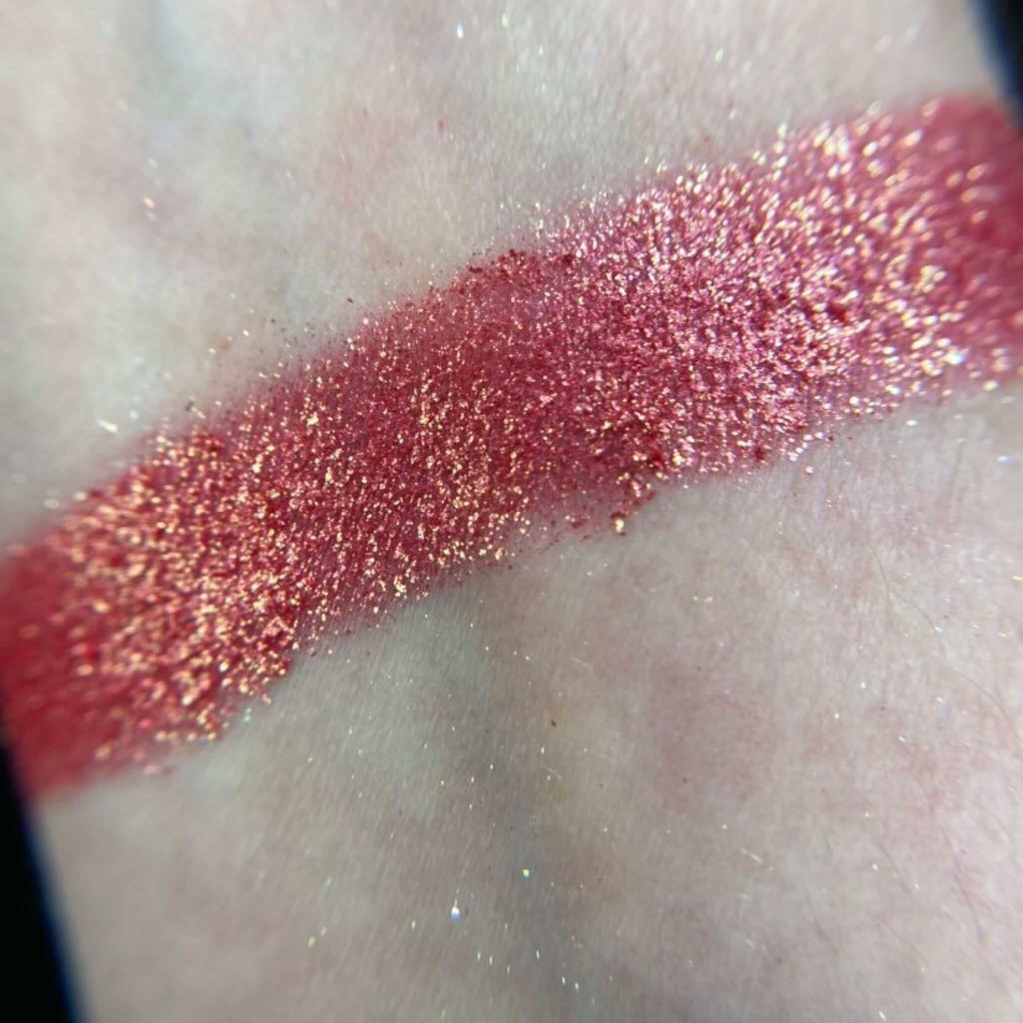 Close-up of shimmering bronze and taupe eyeshadows in sleek black palette with gold accents