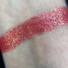 Close-up of shimmering bronze and taupe eyeshadows in sleek black palette with gold accents