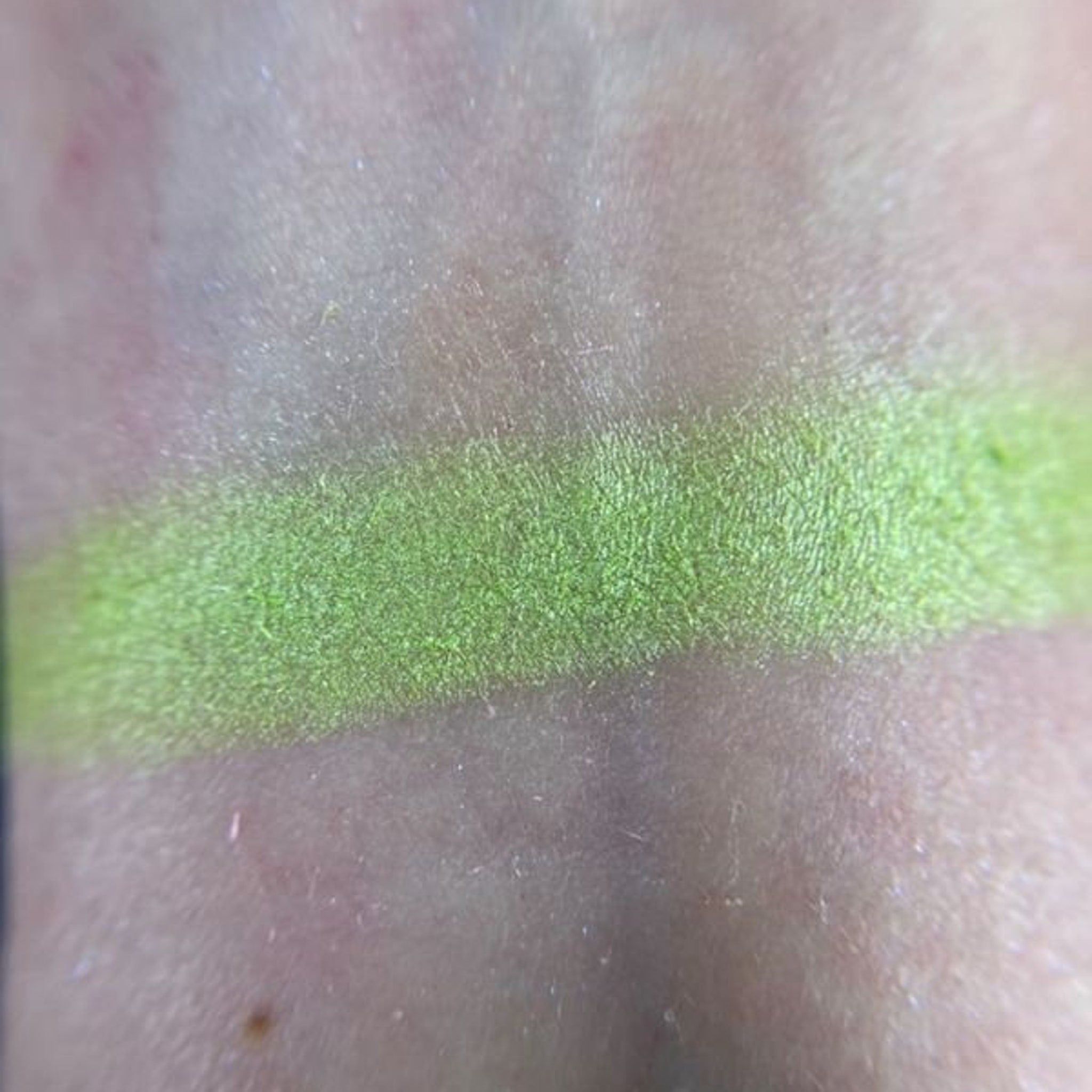 Hand applying shimmery soup-inspired eyeshadow with a blending brush on eyelid
