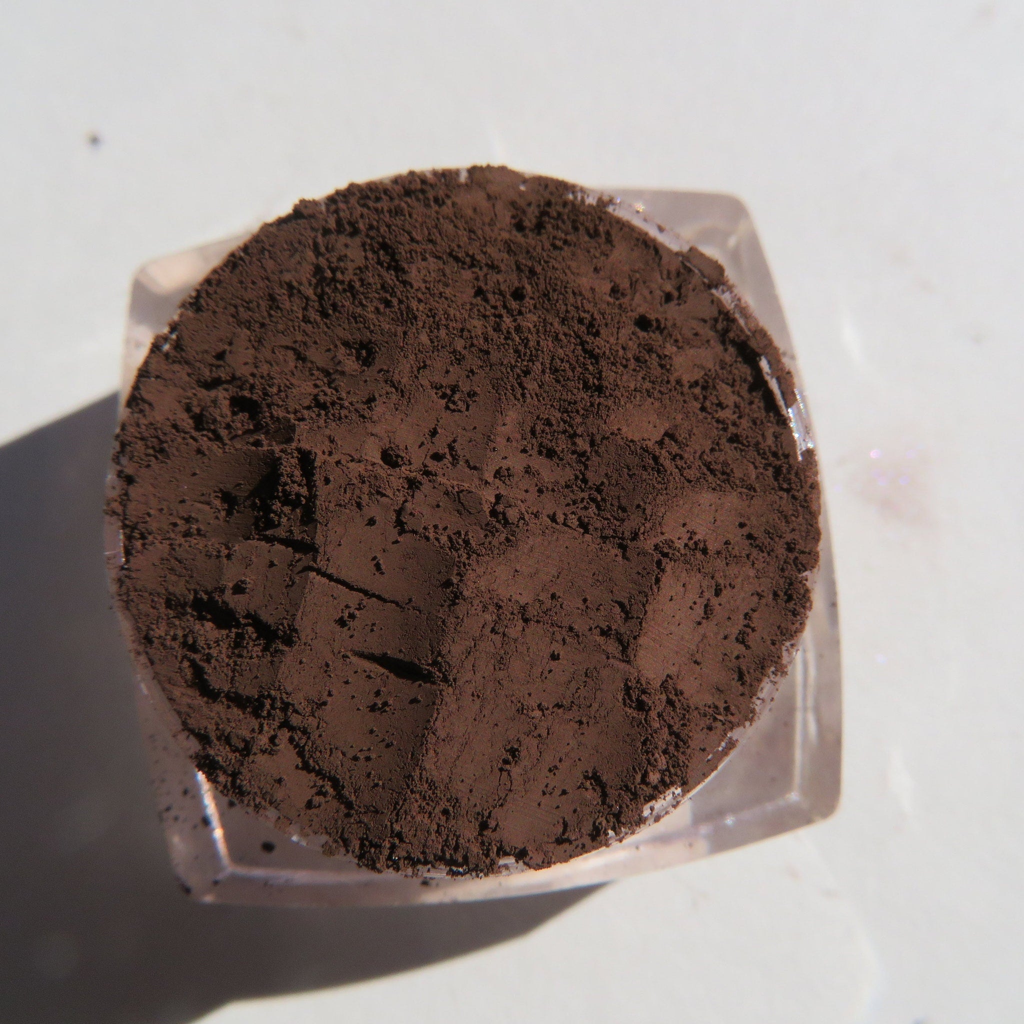Open compact showing matte brown mineral eye shadow powder with vegan label visible