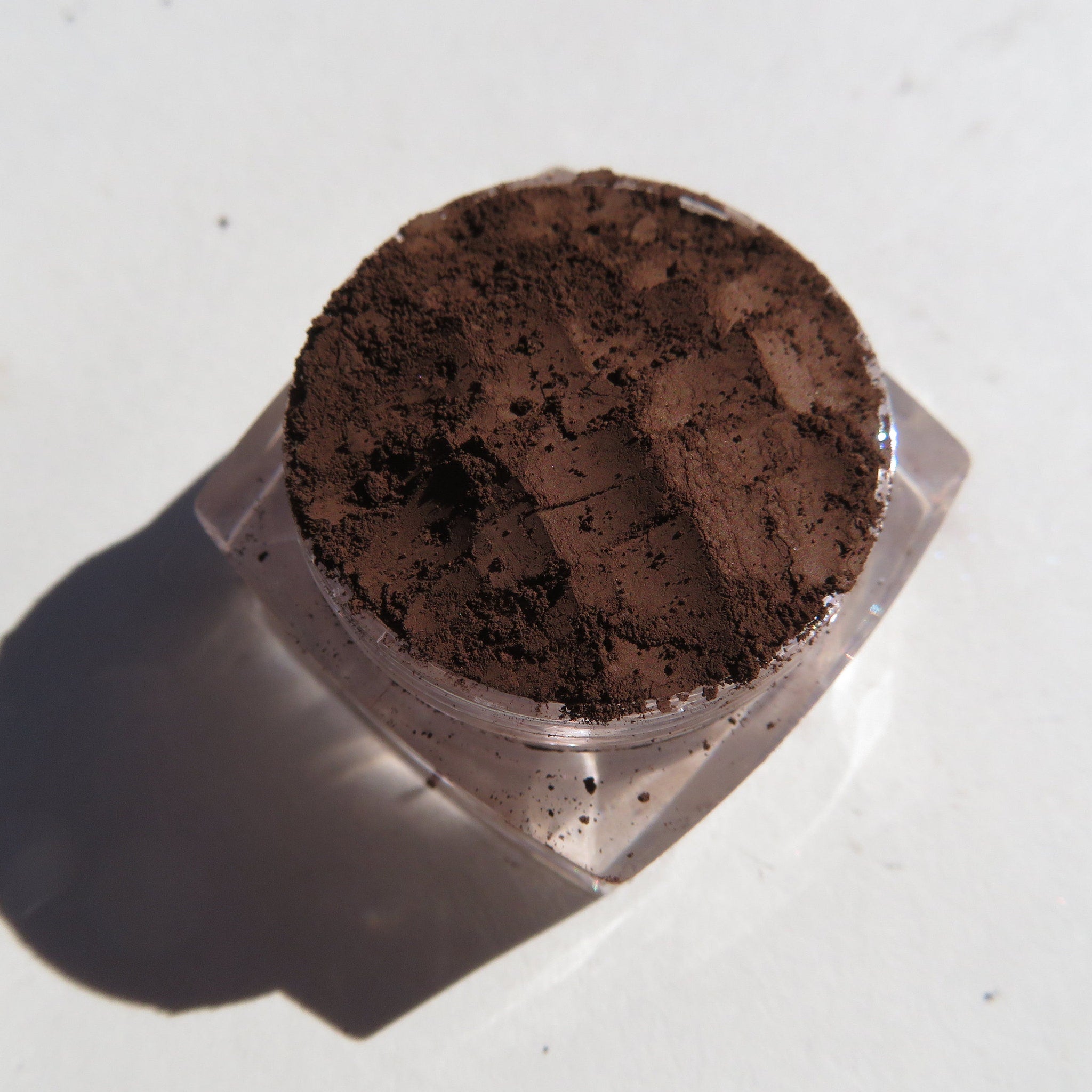 Hand applying matte brown mineral eyeshadow as eyebrow powder with angled brush